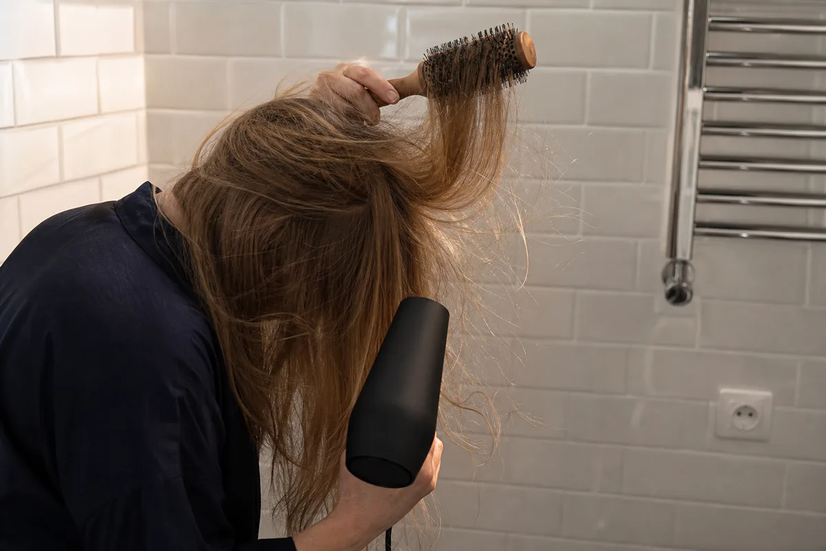 Séchage des cheveux tête penchée en avant avec une brosse ronde en bois